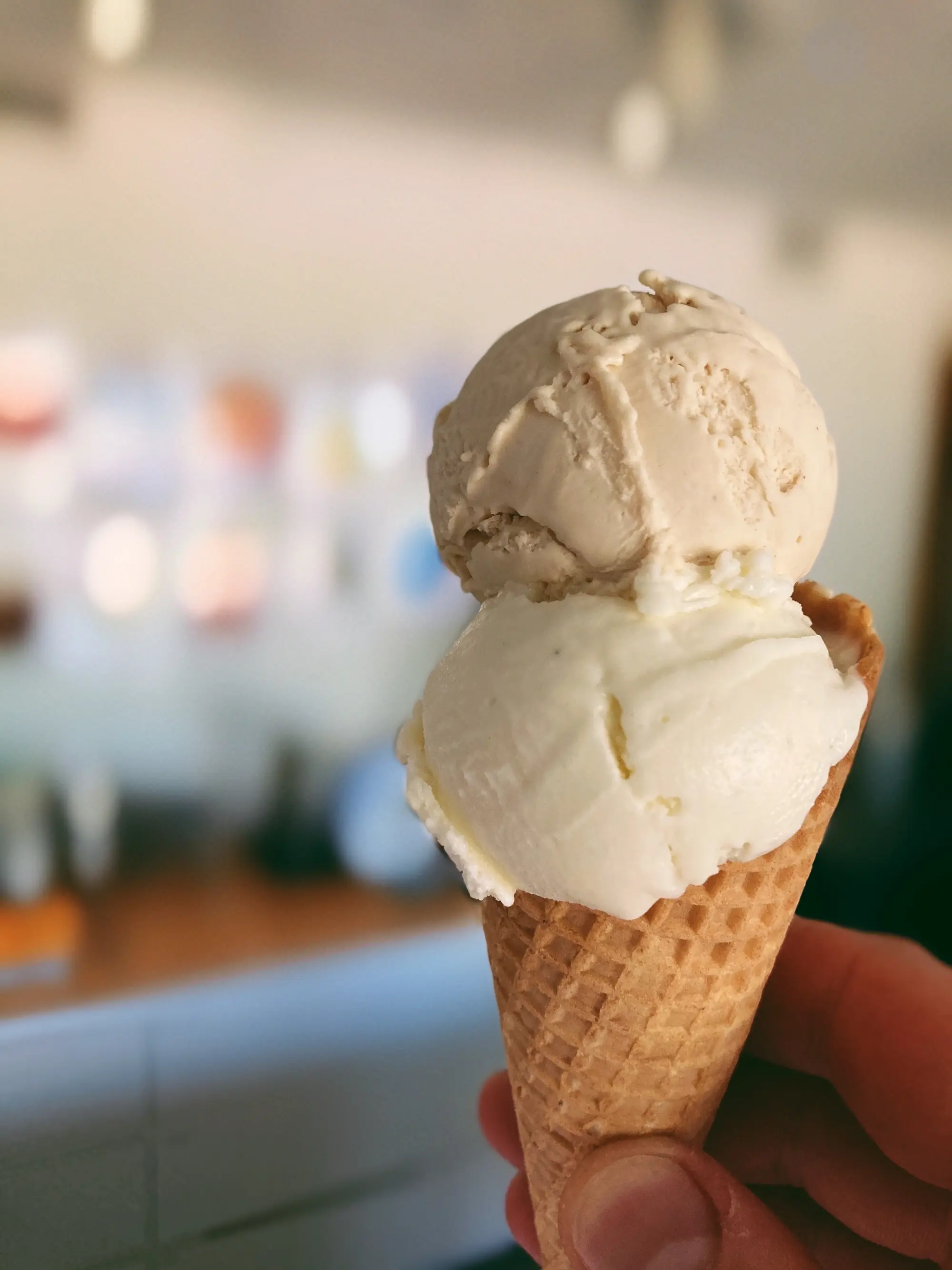 Zwei Kugeln Gelato im Cornet, in der Gelateria in die Höhe gehalten